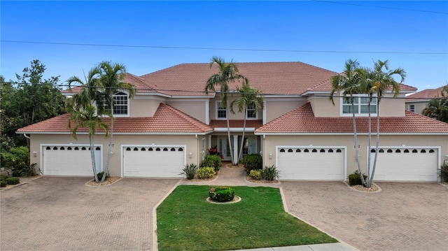 view of front of home with driveway, stucco siding, a tiled roof, and a front lawn