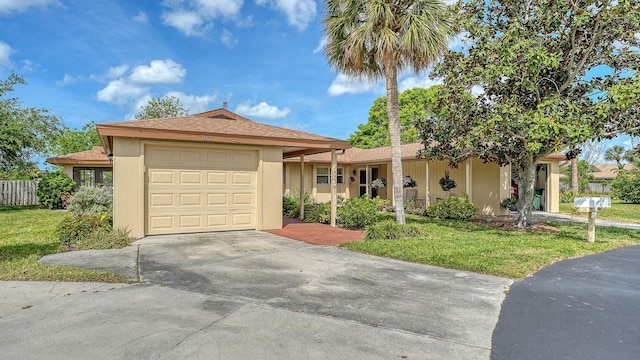 ranch-style house featuring concrete driveway, stucco siding, a front lawn, an attached garage, and a shingled roof