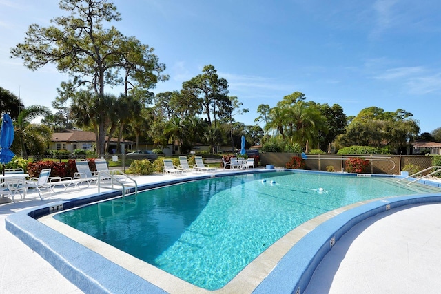 pool with a patio area and fence