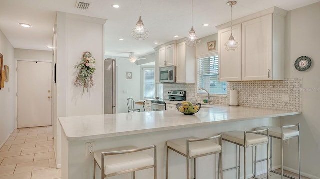 kitchen featuring appliances with stainless steel finishes, light countertops, backsplash, and visible vents