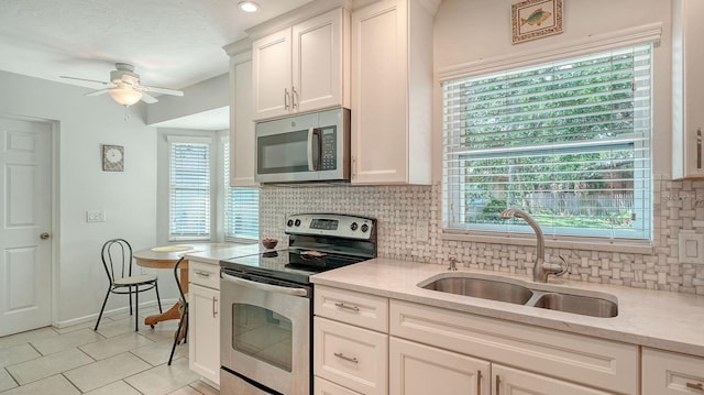 kitchen with a sink, backsplash, ceiling fan, and stainless steel appliances