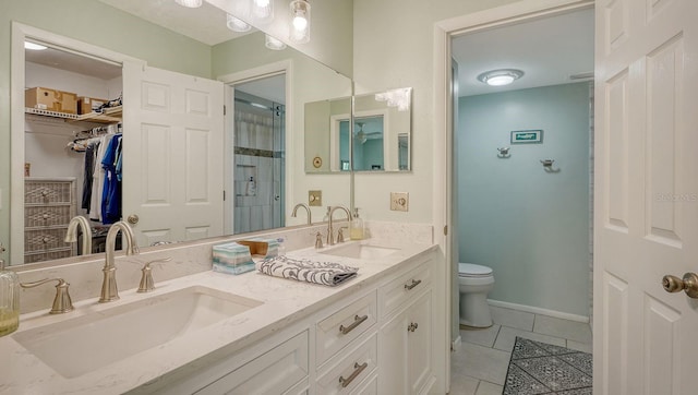bathroom with a sink, tile patterned floors, a walk in closet, and toilet