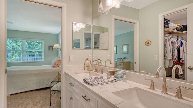 full bath featuring a sink, a walk in closet, double vanity, and connected bathroom