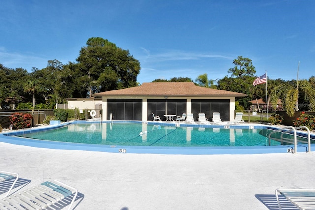 pool featuring a sunroom, a patio, and fence