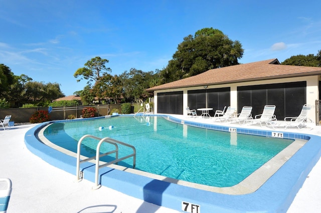 pool with a patio, a sunroom, and fence