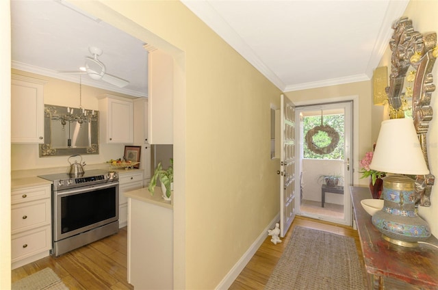 interior space with a chandelier, light wood-style floors, baseboards, and ornamental molding