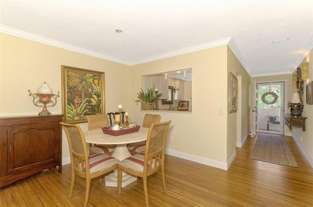 dining area with visible vents, ornamental molding, light wood-style flooring, and baseboards