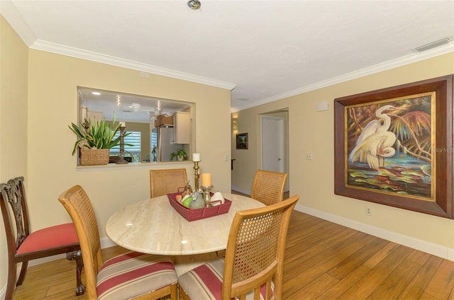 dining area featuring baseboards, ornamental molding, visible vents, and hardwood / wood-style flooring