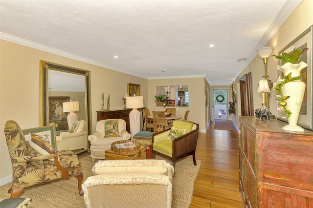 living room featuring visible vents, baseboards, ornamental molding, hardwood / wood-style flooring, and recessed lighting