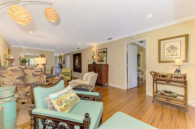 living area featuring hardwood / wood-style floors, crown molding, and baseboards