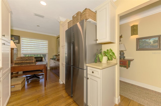 kitchen featuring crown molding, freestanding refrigerator, visible vents, white cabinets, and light wood finished floors