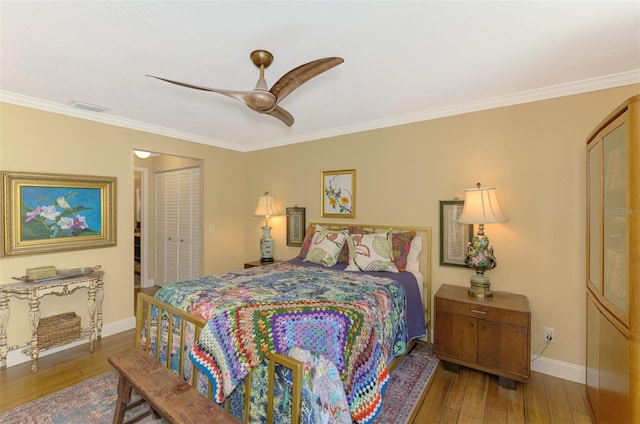bedroom with a closet, baseboards, ornamental molding, visible vents, and hardwood / wood-style floors