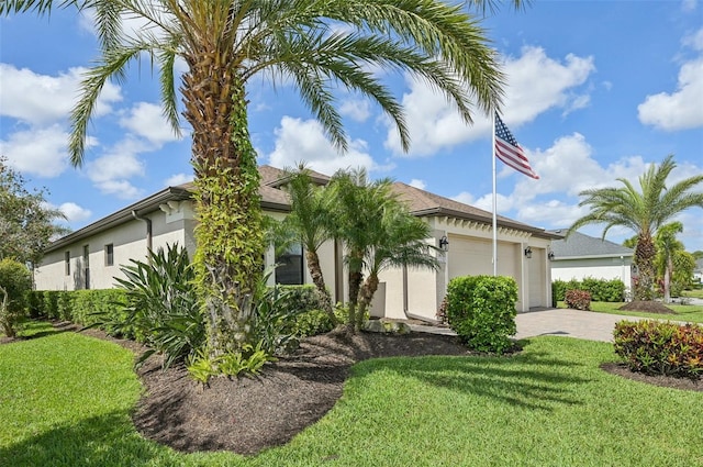 view of front of home with a garage, a front yard, stucco siding, and decorative driveway