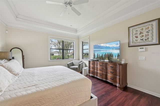 bedroom with a tray ceiling, crown molding, wood finished floors, and baseboards