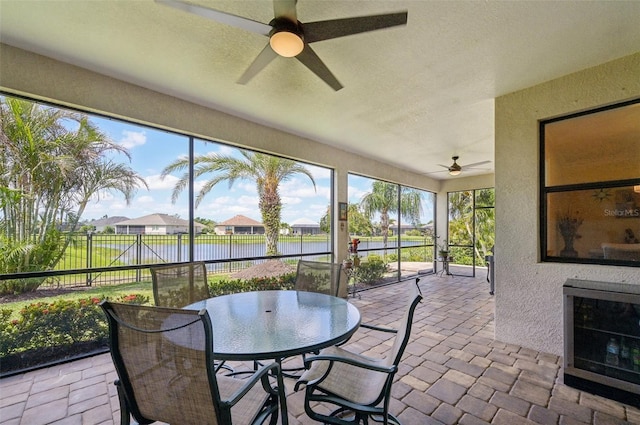sunroom featuring a water view, outdoor dining area, and a ceiling fan