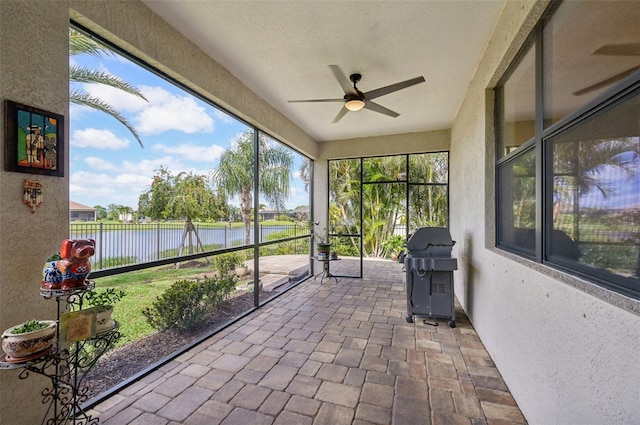 unfurnished sunroom featuring a water view and ceiling fan