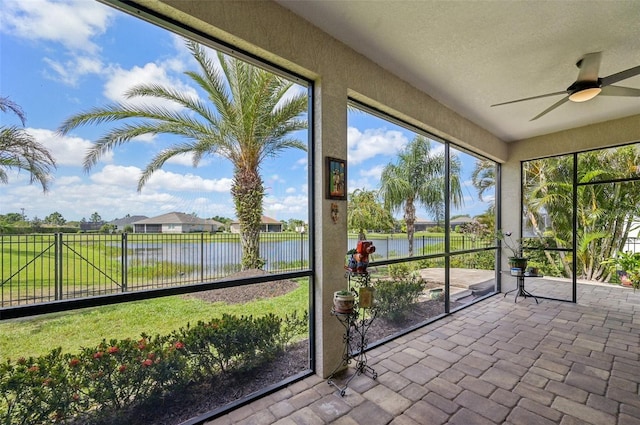 unfurnished sunroom featuring a water view and a ceiling fan