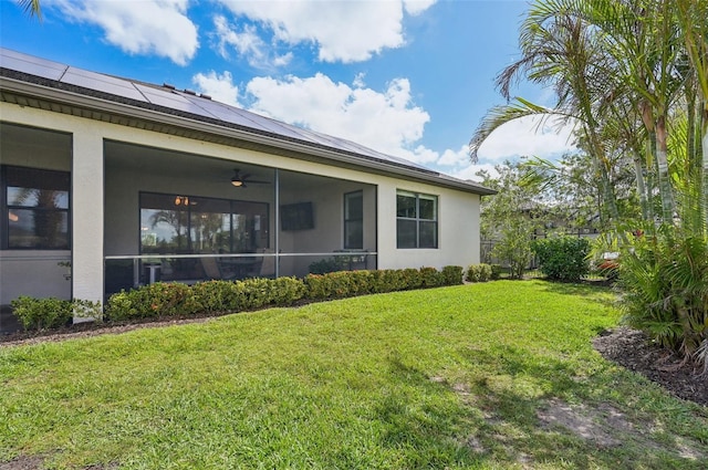exterior space featuring a sunroom, stucco siding, solar panels, and a lawn