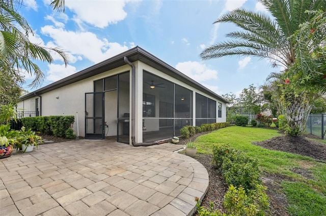 back of property with a sunroom, a patio area, a yard, fence, and stucco siding