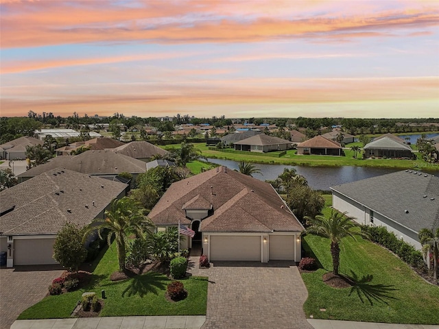 aerial view at dusk featuring a residential view and a water view