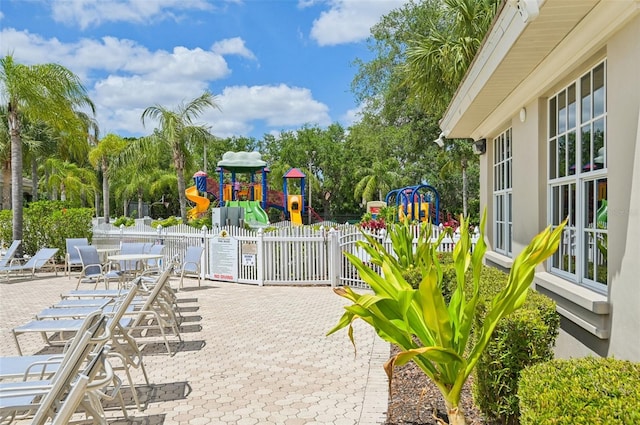 view of patio / terrace featuring playground community and fence