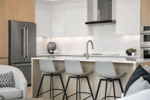 301 Quay Commons Unit 507, Sarasota, FL 34236 - kitchen with appliances with stainless steel finishes, wall chimney range hood, modern cabinets, light countertops, and backsplash