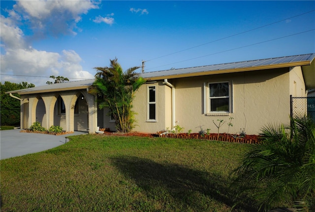 ranch-style house with a front lawn, metal roof, and stucco siding