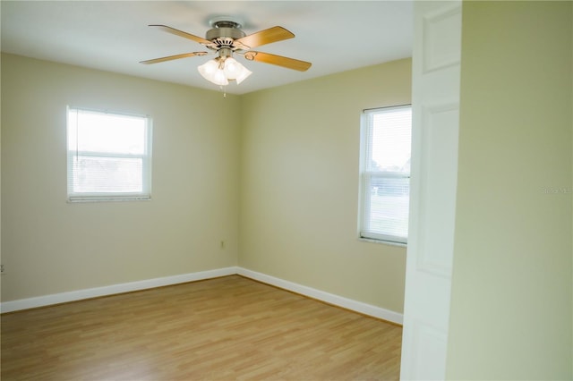 spare room with a ceiling fan, baseboards, light wood-type flooring, and a healthy amount of sunlight