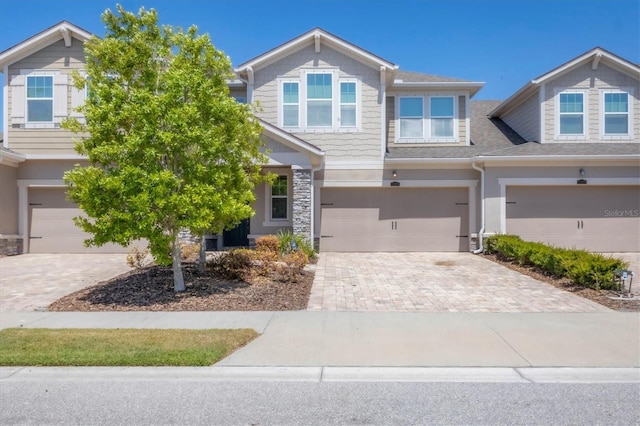 view of front of property with decorative driveway, an attached garage, and stone siding