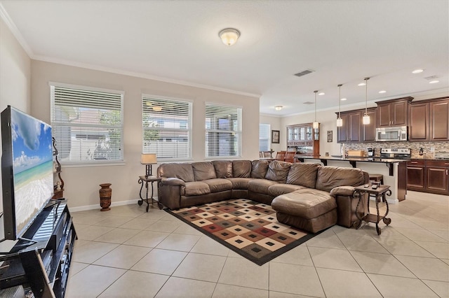 living area featuring visible vents, light tile patterned floors, ornamental molding, and plenty of natural light