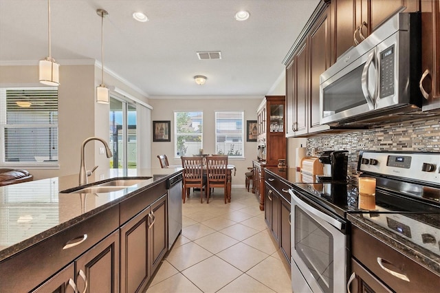 kitchen with dark stone counters, a sink, stainless steel appliances, crown molding, and backsplash