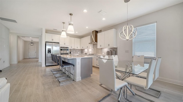 4725 Antrim Dr, Sarasota, FL 34240 - kitchen featuring stainless steel refrigerator with ice dispenser, wall chimney exhaust hood, a sink, tasteful backsplash, and light countertops