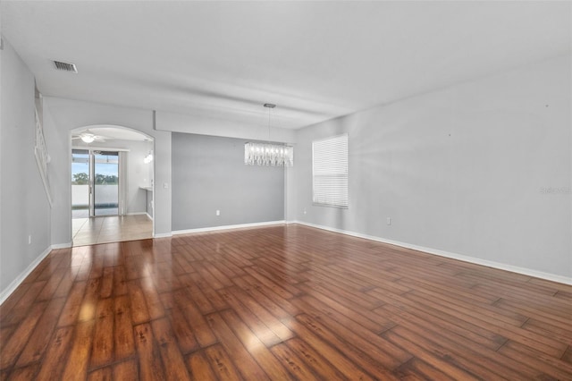 interior space featuring arched walkways, a chandelier, hardwood / wood-style floors, baseboards, and visible vents