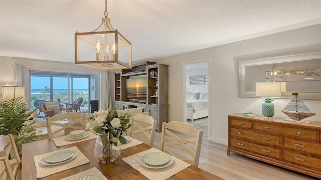 6951 Gulf Of Mexico Dr Unit 14, Longboat Key, FL 34228 - dining area featuring baseboards, light wood finished floors, a textured ceiling, and an inviting chandelier