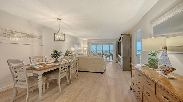 6951 Gulf Of Mexico Dr Unit 14, Longboat Key, FL 34228 - dining area featuring light wood-style floors and an inviting chandelier