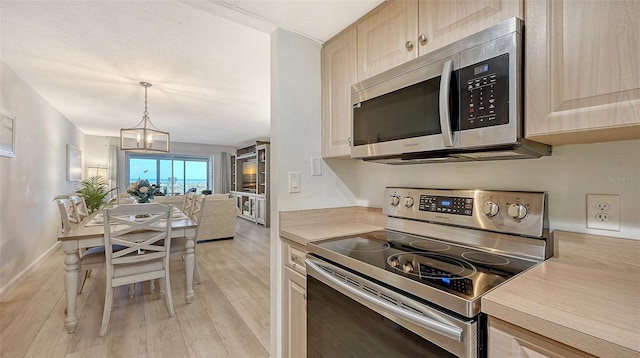 6951 Gulf Of Mexico Dr Unit 14, Longboat Key, FL 34228 - kitchen with baseboards, an inviting chandelier, light countertops, light wood-style floors, and appliances with stainless steel finishes