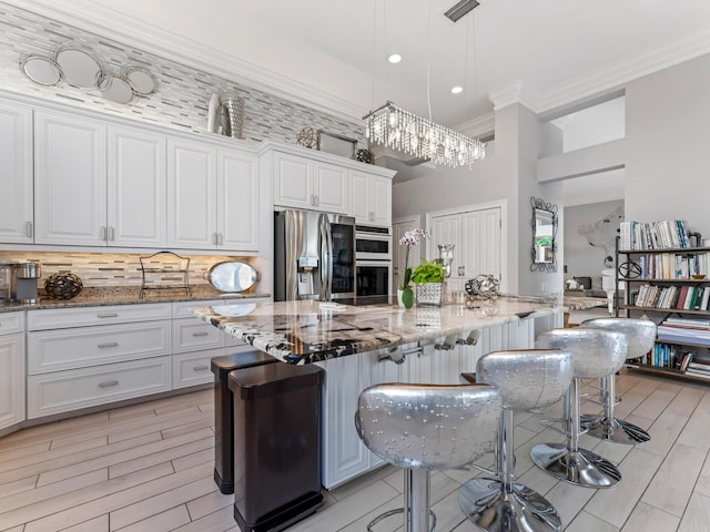 8687 Woodbriar Dr, Sarasota, FL 34238 - kitchen featuring stainless steel fridge, decorative backsplash, crown molding, light stone countertops, and a breakfast bar area