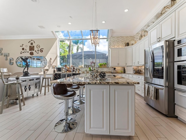 8687 Woodbriar Dr, Sarasota, FL 34238 - kitchen with stainless steel fridge, crown molding, light stone counters, light wood finished floors, and a warming drawer