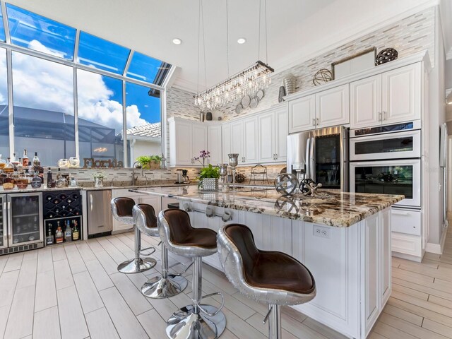 8687 Woodbriar Dr, Sarasota, FL 34238 - kitchen with stainless steel fridge with ice dispenser, wine cooler, light stone counters, recessed lighting, and white cabinets