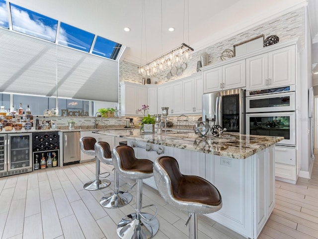 8687 Woodbriar Dr, Sarasota, FL 34238 - kitchen featuring stainless steel fridge, beverage cooler, recessed lighting, light stone counters, and a chandelier