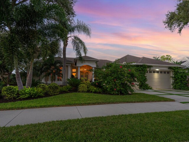 8687 Woodbriar Dr, Sarasota, FL 34238 - view of front of property with concrete driveway, an attached garage, a front lawn, and stucco siding