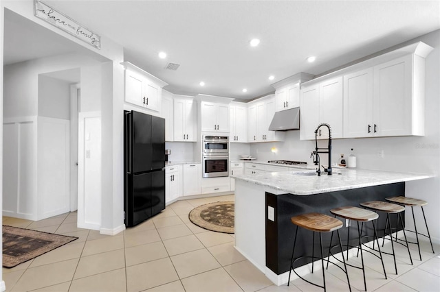 8355 Velda Trl, Sarasota, FL 34241 - kitchen with freestanding refrigerator, under cabinet range hood, a peninsula, stainless steel double oven, and white cabinets