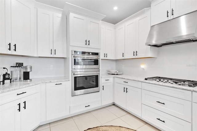 8355 Velda Trl, Sarasota, FL 34241 - kitchen with under cabinet range hood, appliances with stainless steel finishes, white cabinetry, light tile patterned flooring, and light stone countertops