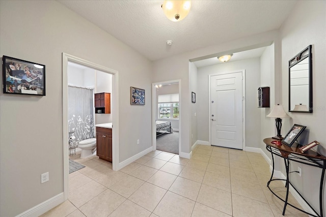 entrance foyer with a textured ceiling, light tile patterned floors, and baseboards