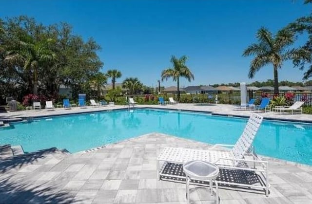 community pool featuring fence and a patio