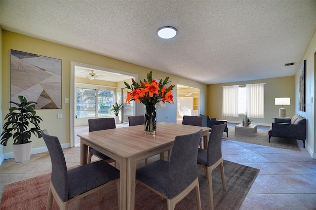 dining area with a textured ceiling, light tile patterned floors, baseboards, and visible vents