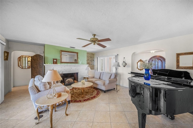 tiled living room with a fireplace, baseboards, a textured ceiling, and ceiling fan