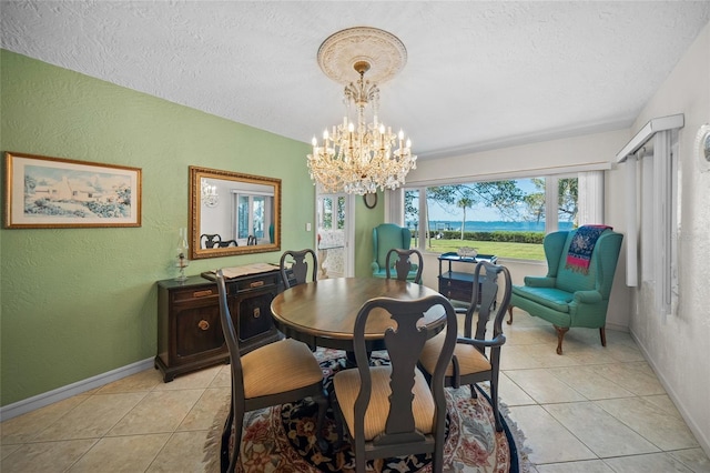 dining area with a notable chandelier, a textured wall, a textured ceiling, and light tile patterned floors
