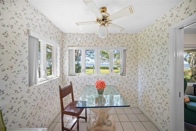 dining area with light tile patterned floors, wallpapered walls, a ceiling fan, and plenty of natural light