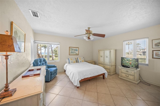 bedroom featuring light tile patterned flooring, a textured ceiling, a ceiling fan, and visible vents